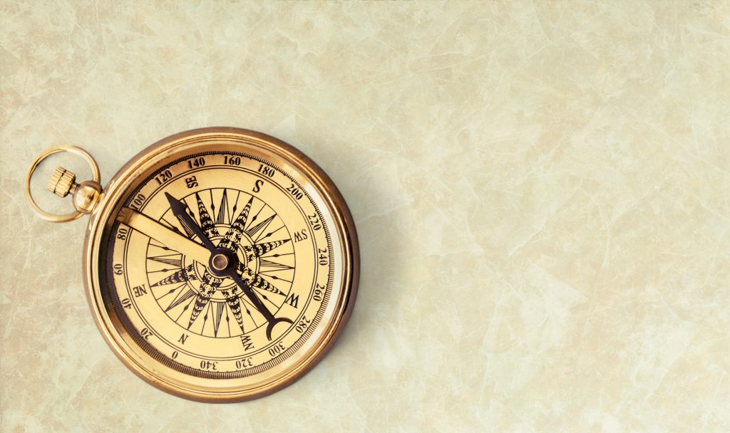 Brass antique compass on beige background