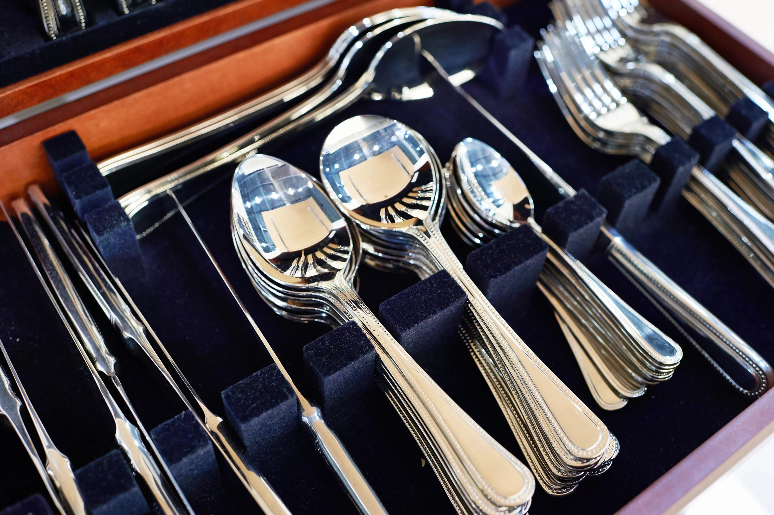 Cutlery forks, spoons and knives on dark blue velvet