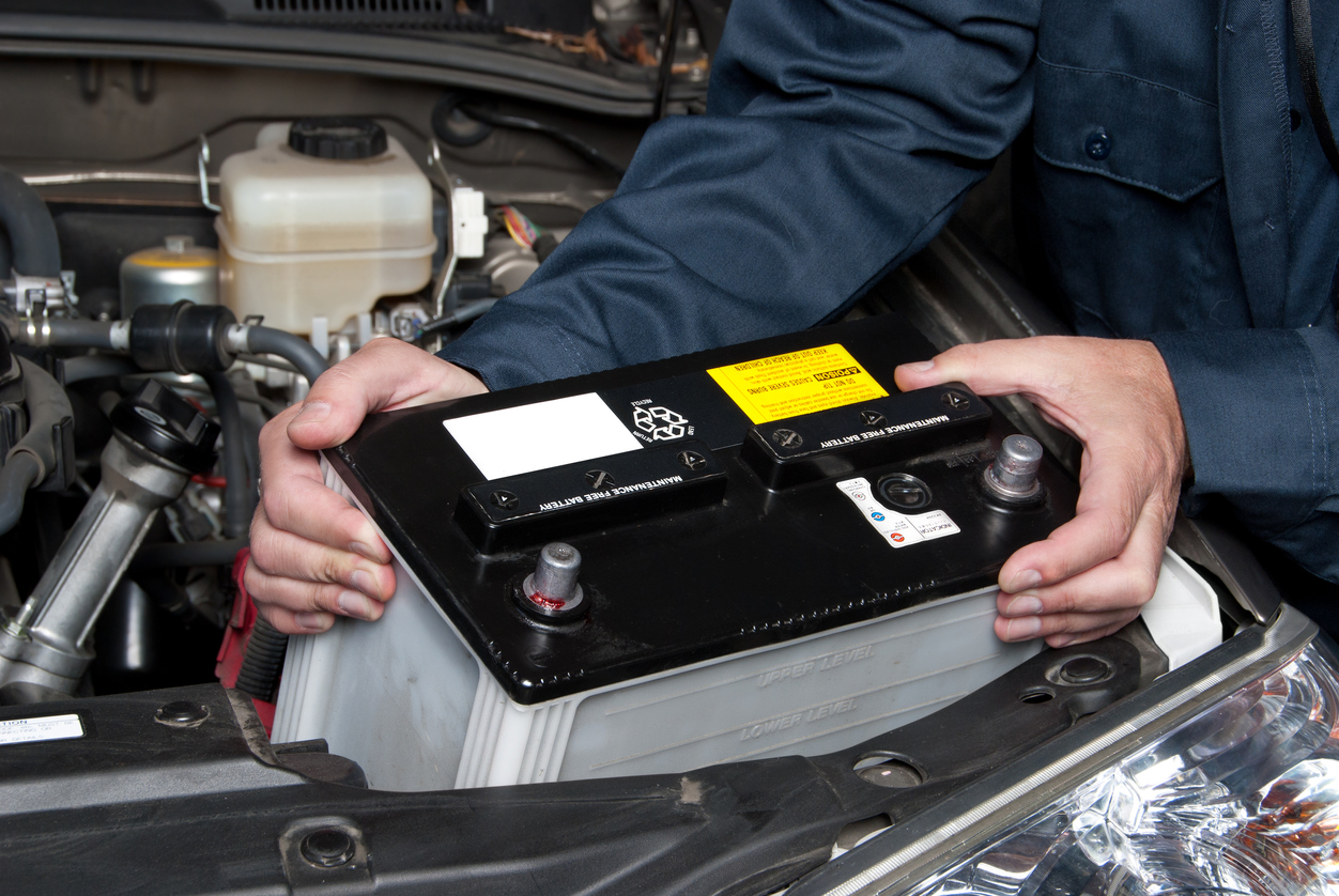 Auto mechanic replacing car battery