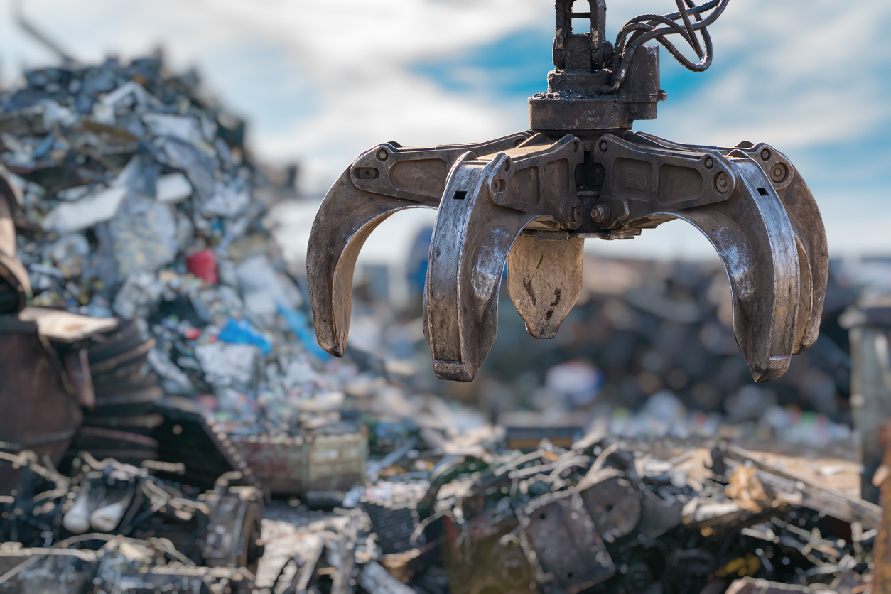 Close-up view on mechanical arm claw of crane at landfill.