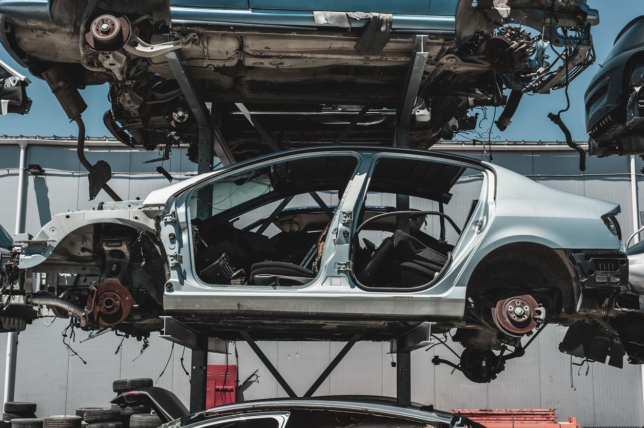 Crashed car and auto parts in a dismantling yard.