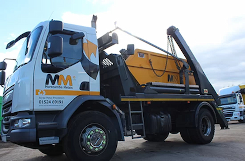 A yellow and white skip truck labelled with Morecambe Metals Logo
