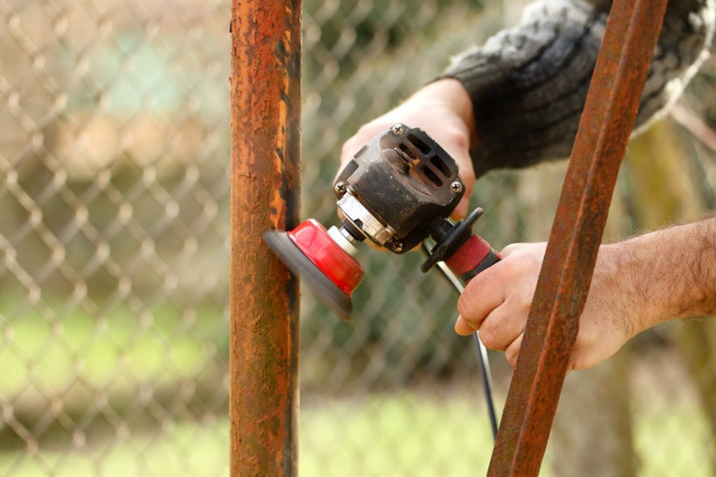 A person using a grinder to polish a metal pole
